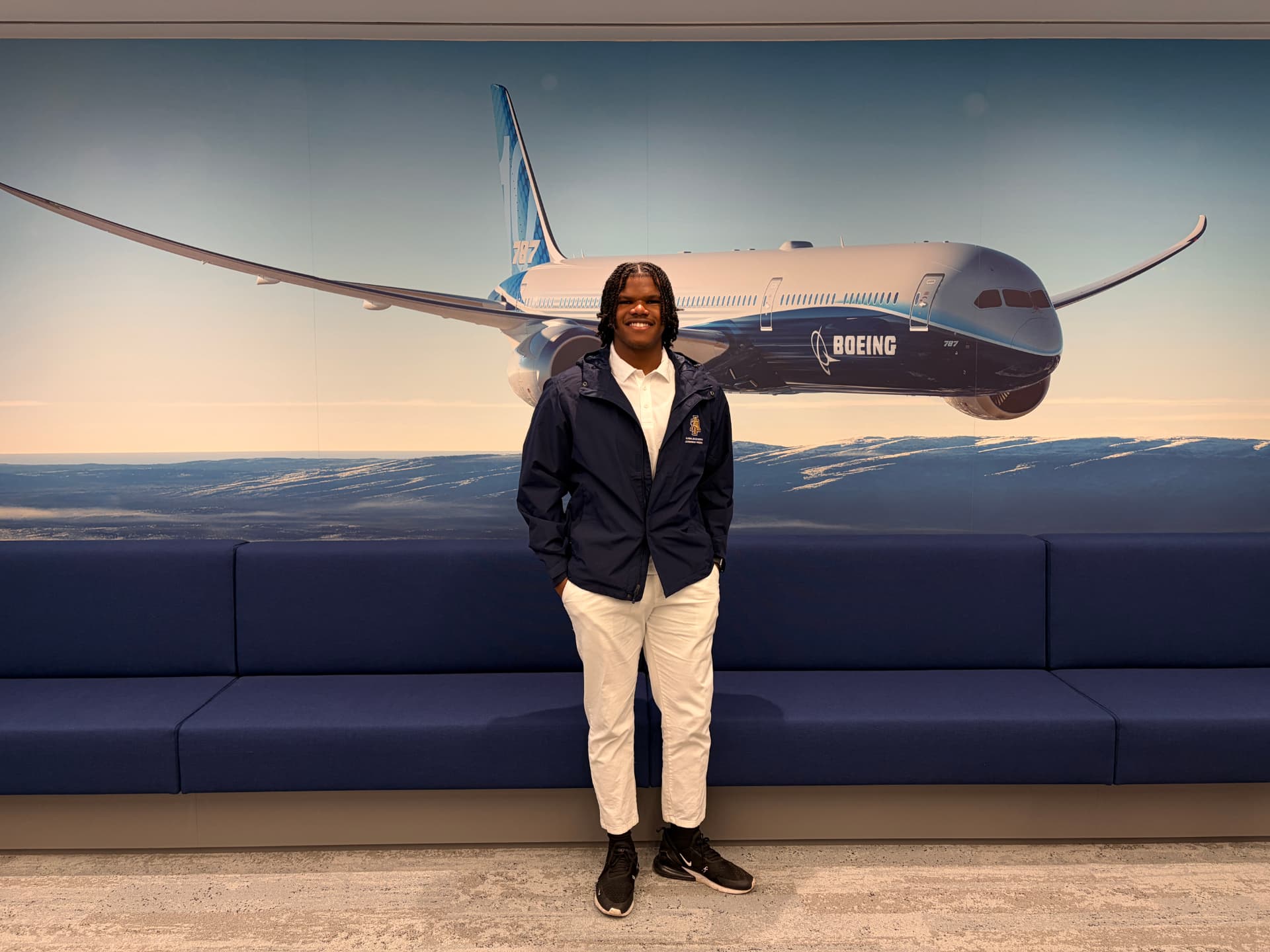 Devin Minor standing in front of a Boeing 787 mural during the Global Engineering Leadership Program