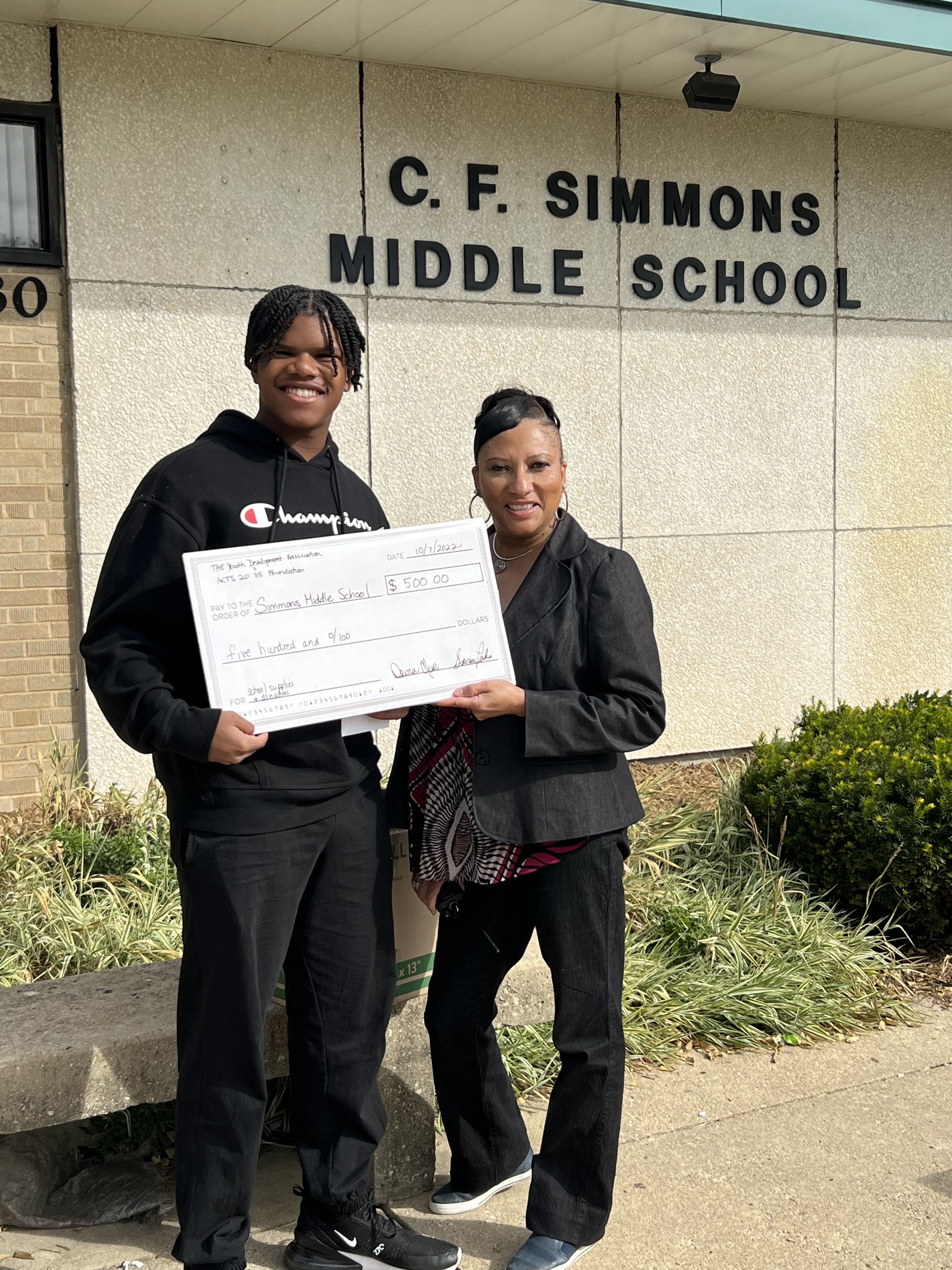 Devin R. Minor presenting a five hundred dollar donation check from The Youth Development Association to C. F. Simmons Middle School for school supplies and donations